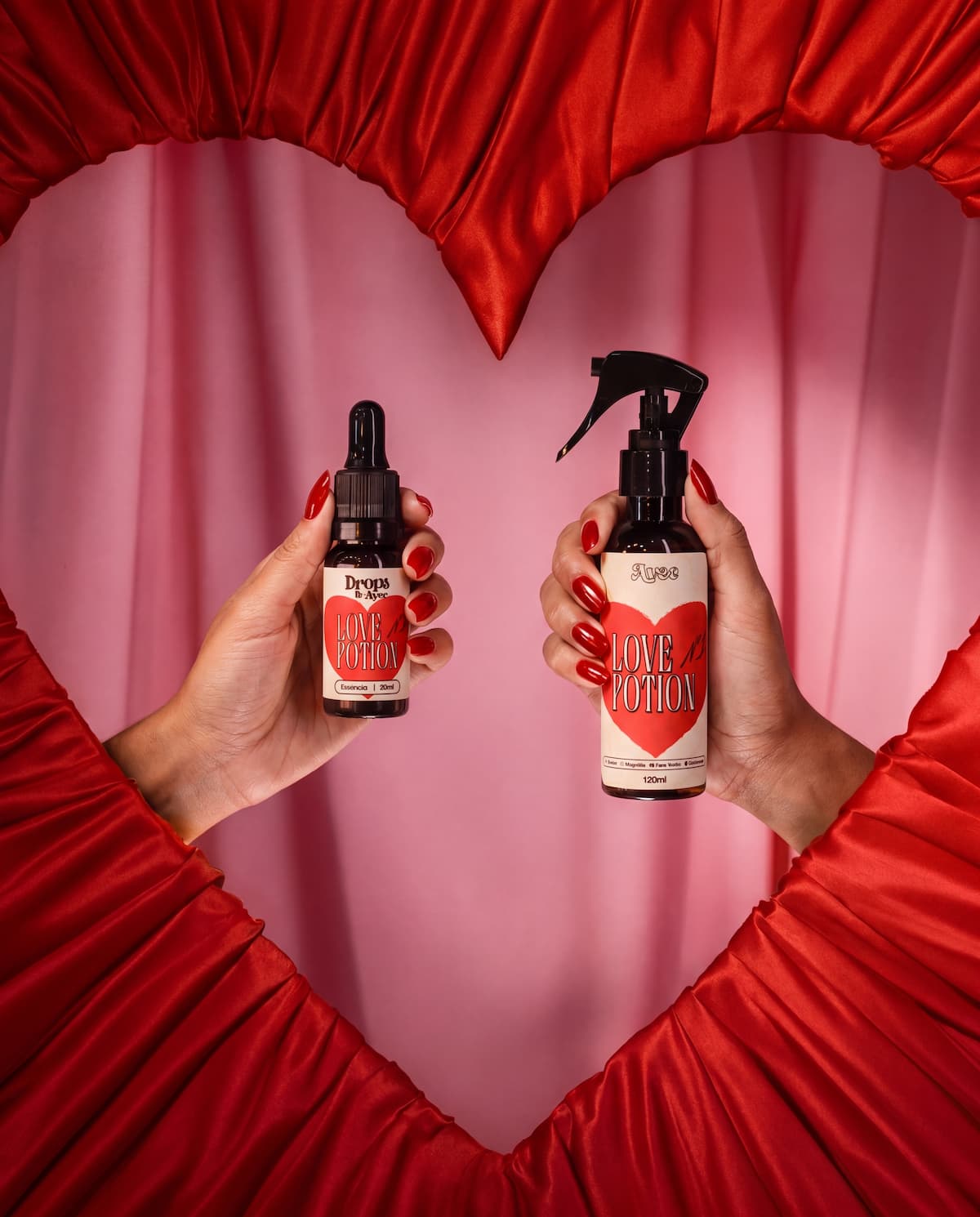 Mãos segurando os produtos Love Potion da Avec, emolduradas por um coração de cetim vermelho